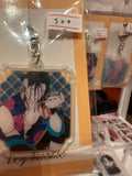 Acrylic keychain with long-haired character in black-and-red floral costume – photographed in packaging