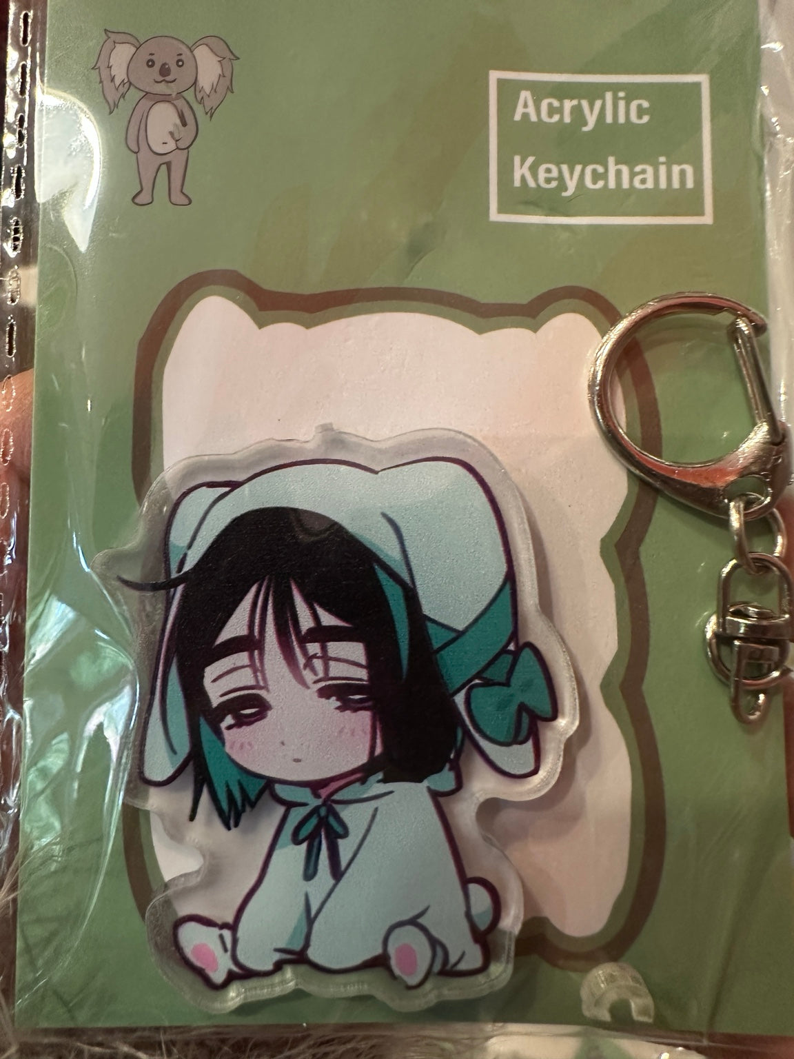 Black-haired character in teal bunny animal onesie acrylic keychain